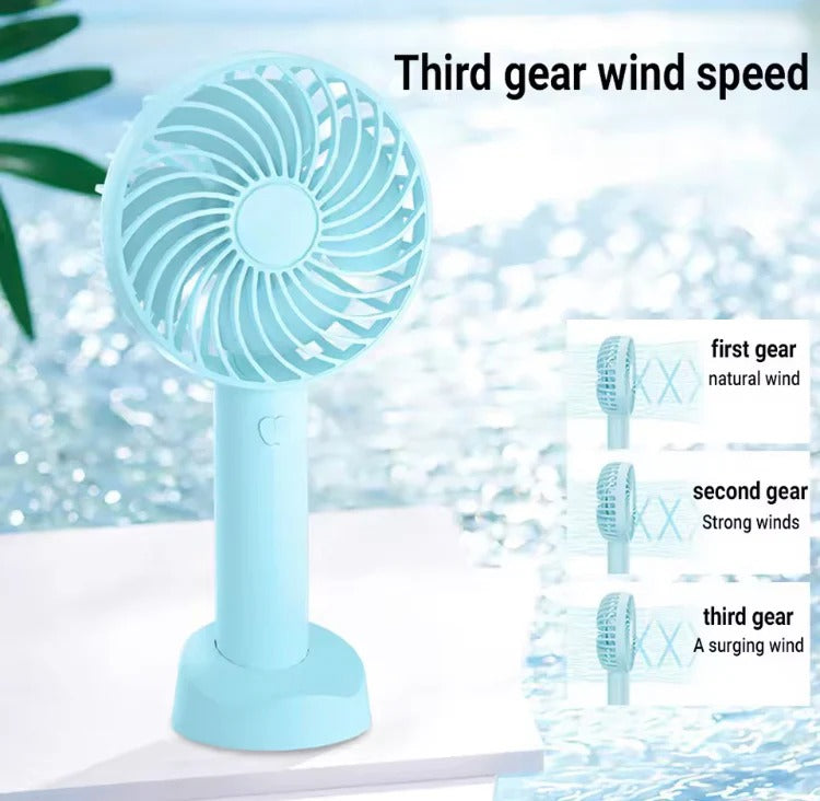 Portable fan with speed settings labeled on a blurred natural background