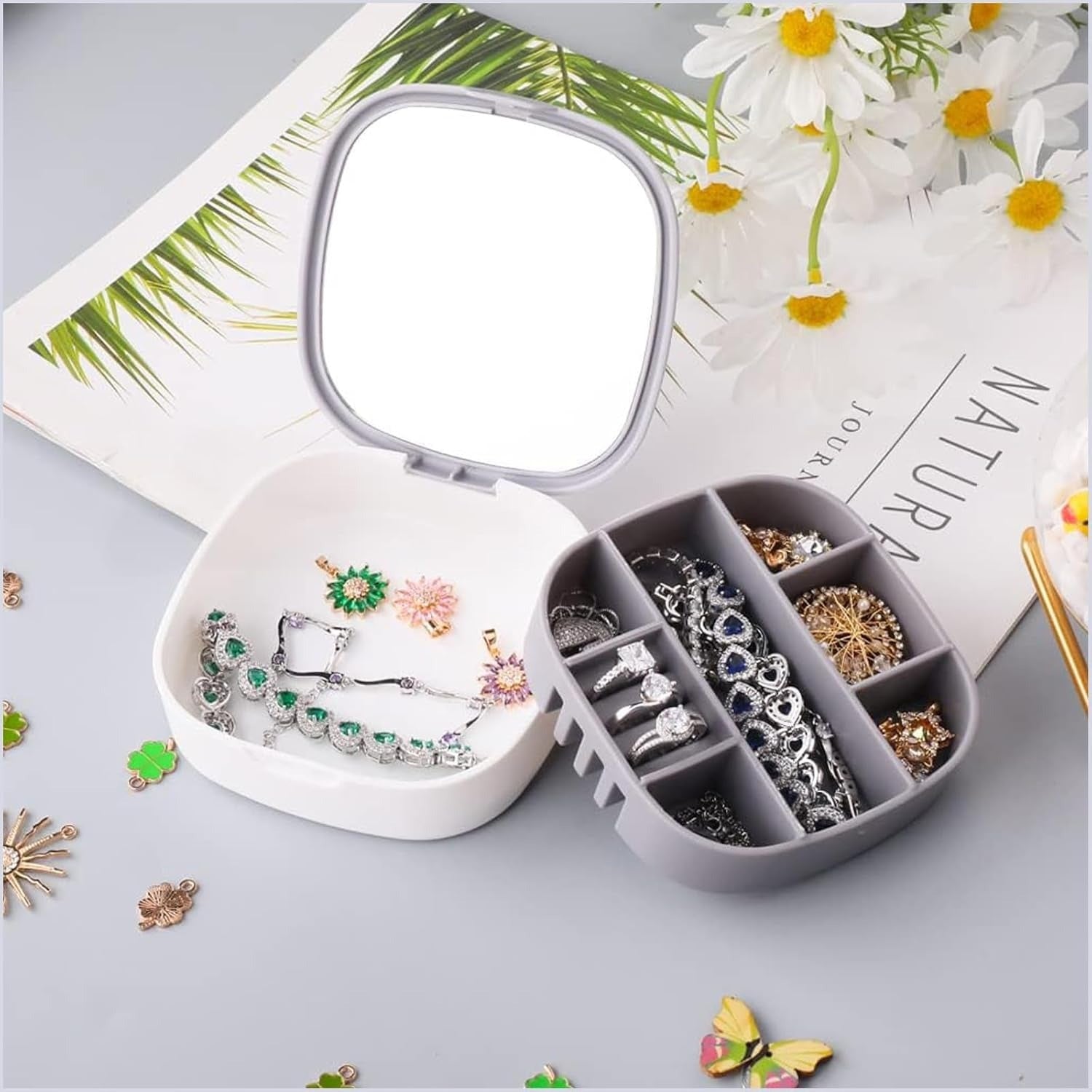 Jewelry organizer with rings and a mirror on a magazine with flowers