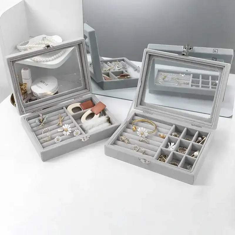 Gray jewelry box with mirror lid containing various earrings on a white background