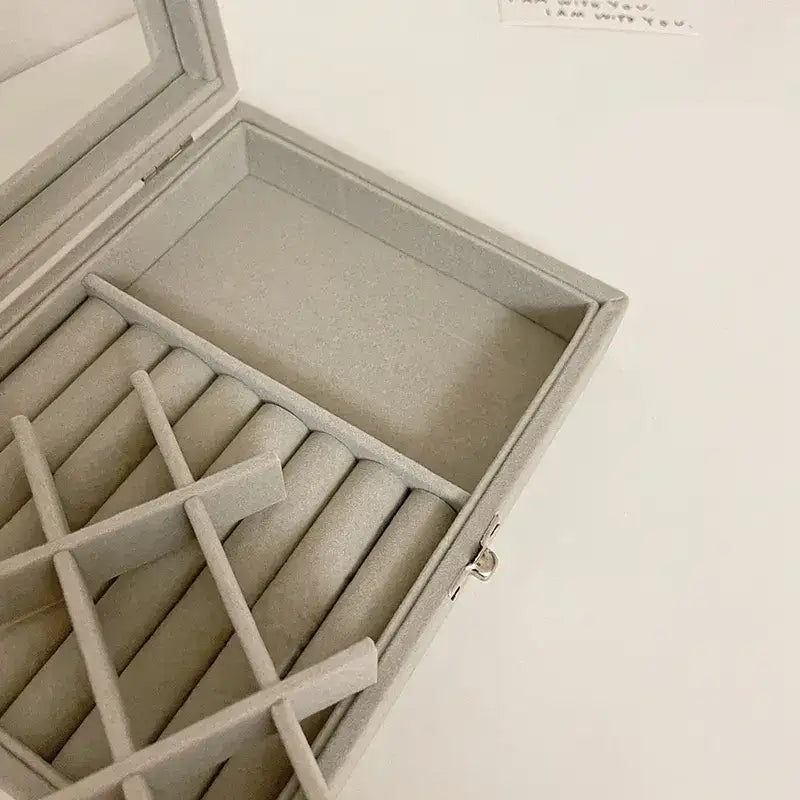 Open beige jewelry box with compartments on a light background