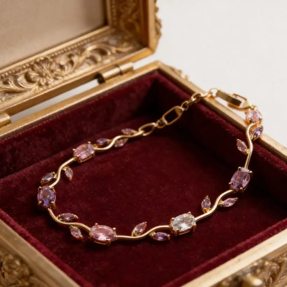 Gold bracelet with pink and purple gemstones in an ornate gold box.