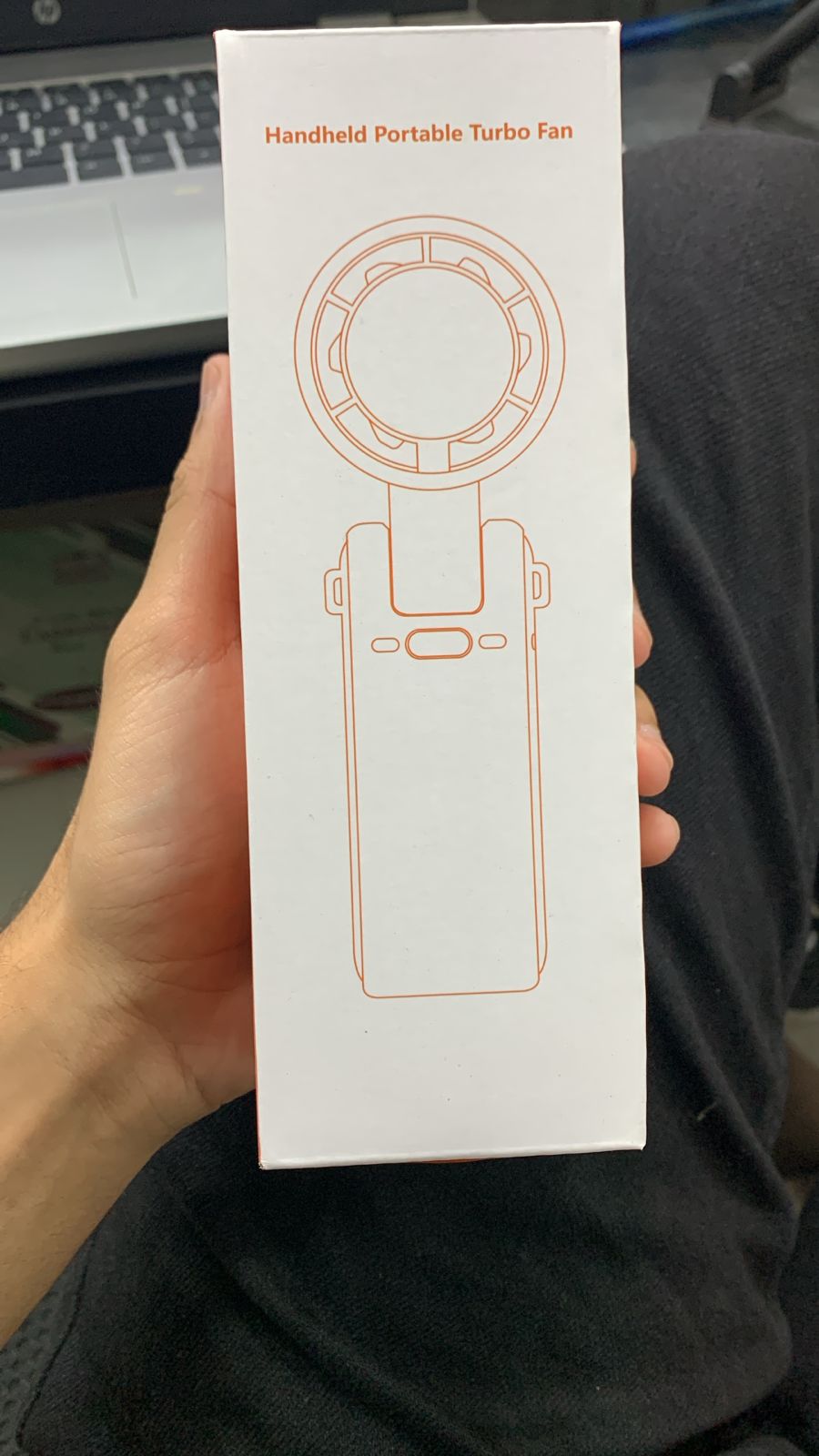 Handheld portable turbo fan packaging held by a person with a blurred background