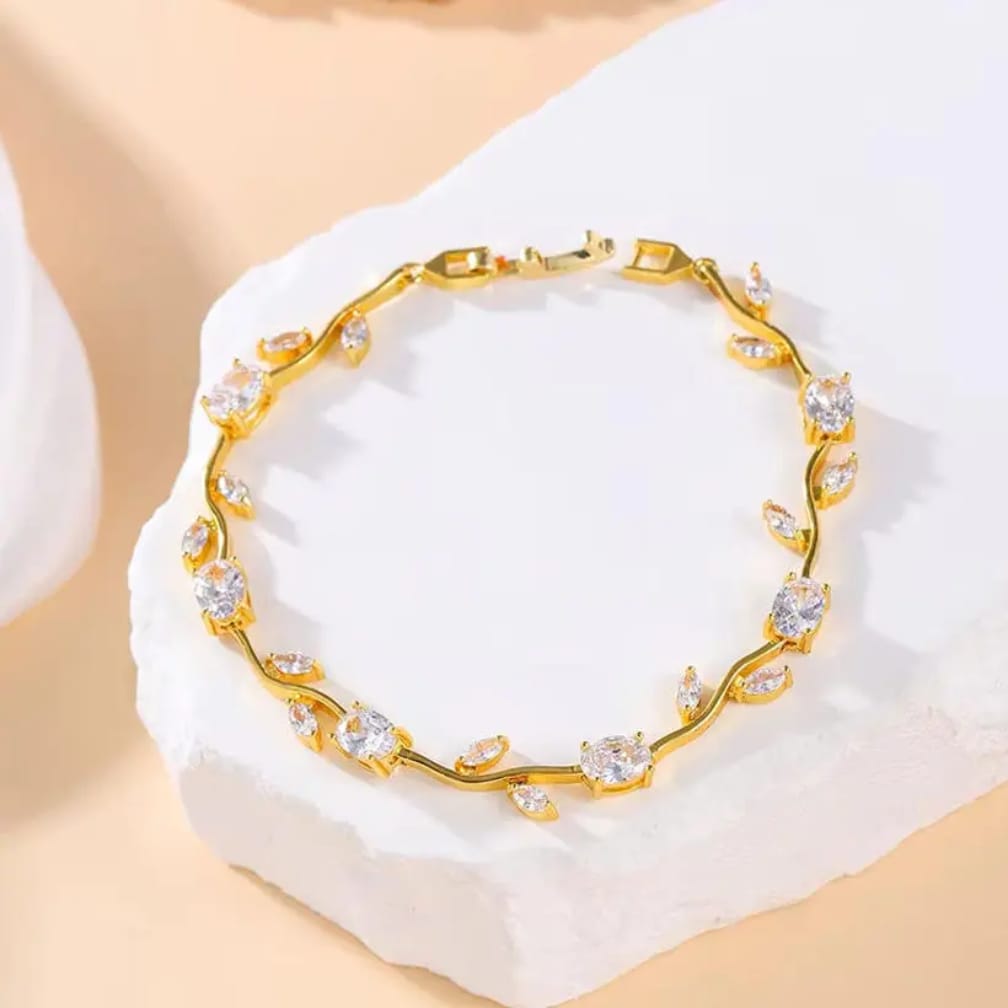 Gold bracelet with clear stones on a white stand