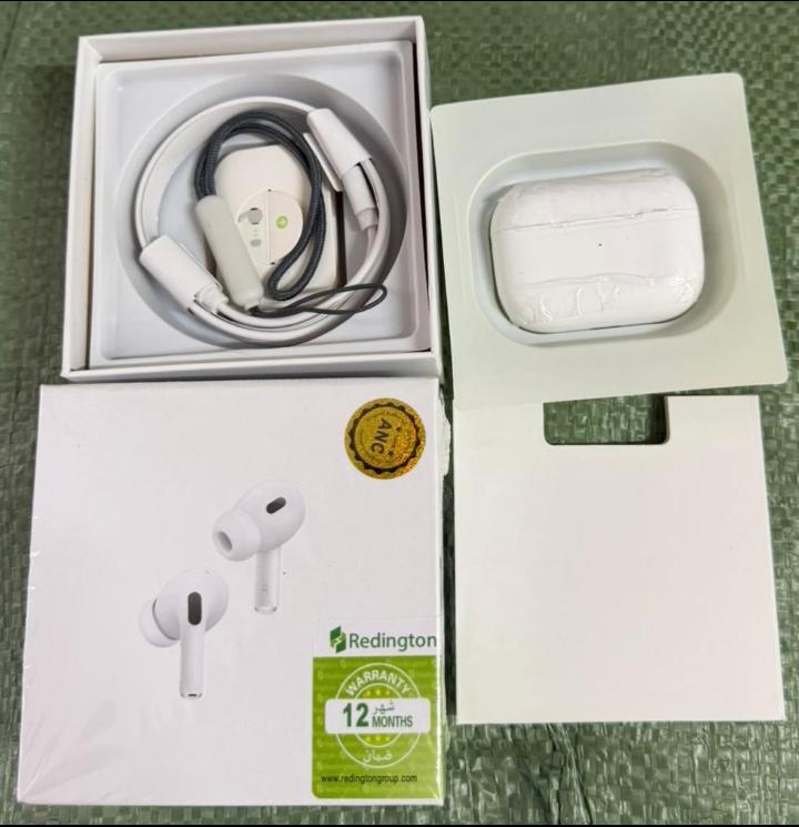 White wireless earbuds with charging case and Redington branded box on a green surface